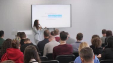İzleyiciler teknoloji seminerinde sunucuyu dinliyor. Etkileşime ve çatışmaya odaklan.