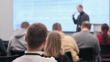 Odaklanmış seyirciler iş konferansında ilgi çekici sunumu dinlerler. Profesyonel ortam öğrenme ve ağ kurma olanaklarını artırır.