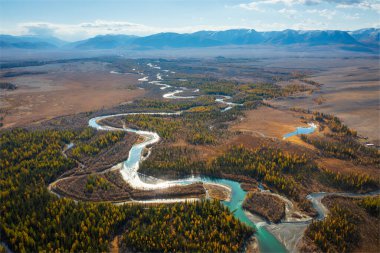 Sonbahar ormanı ve kıvrılan nehir uzak sıradağlara doğru ilerliyor. Titreşimli sonbahar renkleri.