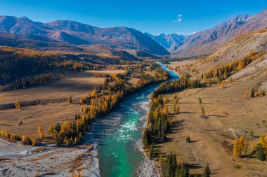 Sonbahar ormanı ve dağlık ufukta turkuaz bir nehri olan bir vadinin nefes kesen manzarası canlı doğal manzaraları ve huzurlu huzuru yakalıyor. Doğa ve seyahat için ideal.