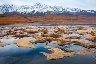 Serene autumn view of a vibrant plain with lakes and distant snow-covered peaks. clipart