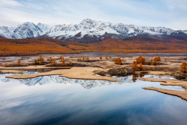 Karlı dağlar ve sonbahar ağaçları göle yansıyarak huzur ve doğal manzarayı resmediyor..