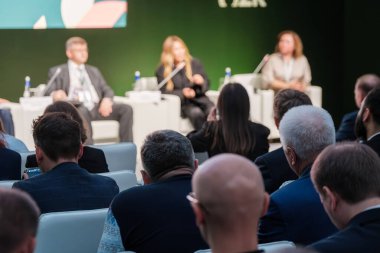 Resmi katılımcı kitlesiyle yapılan şirket paneli tartışması gözlemler ve notlar yapıyor. İş iletişimi ve profesyonel etkileşim için ideal.