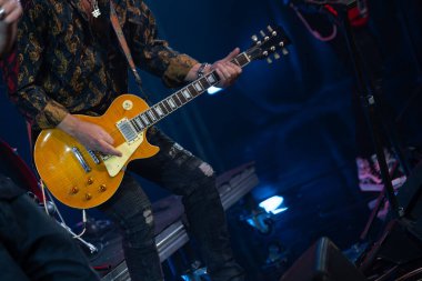 Canlı performans sırasında sahnede tutkulu bir şekilde elektro gitar çalan müzisyen rock müzik titreşimleri ve enerji sergiliyor..