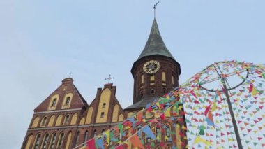 Kaliningrad 'daki tarihi kilise binası tuğla mimarisi, uzun saat kulesi ve renkli dekoratif bayraklar ile canlı bir atmosfer yaratıyor..