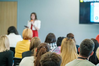 Bir konuşmacıyı dinleyen özenli izleyicilerle iş toplantısı semineri. Konferans odasında önemli konuları tartışan profesyonel bir sunum.