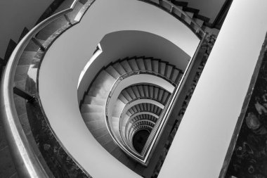 Siyah ve beyaz görüntü üst taraftan zarif kıvrımlı sarmal merdivenleri yakalıyor..