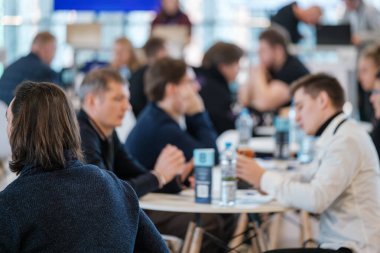 İş dünyasından profesyoneller tartışmalara giriyor, ağ oluşturma etkinliğinde fikirlerini paylaşıyorlar. Bulanık arkaplan, modern kurumsal ortamda etkileşime, işbirliğine ve takım çalışmasına odaklanma yaratır.