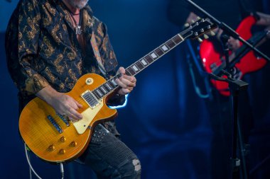 Elektro gitarist canlı rock konserinde tutkuyla çalıyor. Karanlık sahne aydınlatması karamsar bir atmosfer yaratır, müzik ve performansa odaklanır..