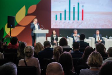 Kürsüde konuşmacıların katıldığı bir iş konferansı. Profesyonel ayarda verileri gösteren sunum ekranı.