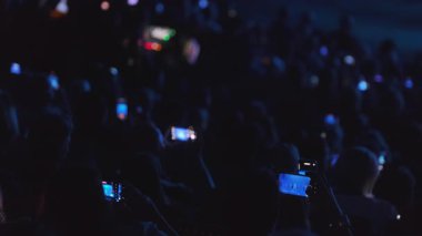 Halka açık bir etkinlikte kalabalık üyeleri, performanslarda modern teknolojinin rol oynadığını gösteren düşük ışık ayarlı akıllı telefonlarla anları yakalıyor.. 