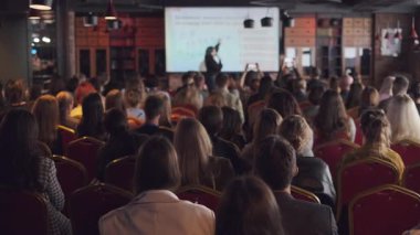 Modern bir ortamda resmi bir sunuma katılan, eğitim ve ağ kurma olanaklarına odaklanan, yenilikçi fikirleri paylaşmak ve tartışmak için profesyonel iş ortamı yaratan büyük kitle