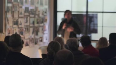 Modern mekanda sunuma katılan bir grup insan konuşmacı ve fotoğraflara odaklandı.