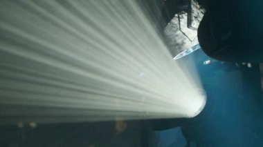 Sahne ışıklandırması toz parçacıkları arasında canlı ışınlar yaratıyor, tiyatro atmosferini çağrıştırıyor ve vurgu yapıyor..