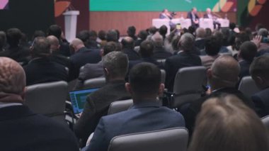 Kalabalık bir kitle resmi bir seminere veya iş konuşmasına katılmak üzere bir konferans odasında toplandı..