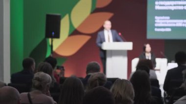 Profesyonel iş konferansı devam ediyor. Konuşmacı resmi ortamda izleyiciye hitap ediyor..
