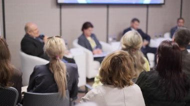 Panelistleri dinleyen bir grup katılımcı konferans sırasında mesleki konuları ya da etkinlik ayarlarında atölye oturumlarını tartışır