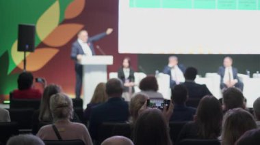 Profesyonel çevrede katılımcı kitleye sunum yapan konuşmacı ile konferans ayarları. Çeşitli katılımcılar oturumu gözlemler ve etkileşirler.