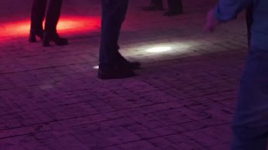 Canlı ışıklarla aydınlatılmış bir disko zemininde dans eden insanların görüntüsü havayı ve enerjiyi artırır..