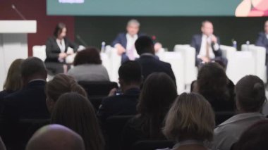 Profesyonel bir konferansa katılan seyirciler, konuşmacıların sahnede fikirlerini ve tartışmalarını paylaşıyorlar. Olayda işbirliği ve bilgi paylaşımı vurgulandı.