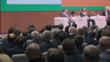 Profesyonel bir sahnede panel konuşmacılarının katıldığı resmi bir tartışmaya geniş kitle katılıyor..