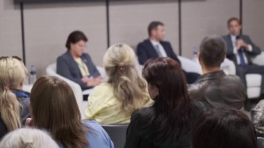 Seyirciler bir iş paneli sırasında profesyonel konuşmacılara bakıyorlar. Bağlı katılımcılar aktif olarak katılırlar.