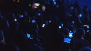 Konferansa katılanlar, karanlık bir oditoryum ortamında akıllı telefonları kullanarak canlı performans kaydediyorlar. Kalabalık film çekiyor ve etrafındaki loş ortamda aydınlatılmış gösteriye odaklanıyor.