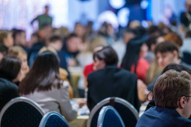 Büyük grup yoğun bir profesyonel toplantıda etkileşim içinde, işbirliği ve tartışmaları teşvik ediyor.