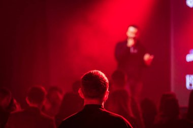 Kırmızı ışık efektli seyircilerin sahne arkası görüntüsü. Arka planda bulanık kalabalıkla sahne etkinliğine odaklan.