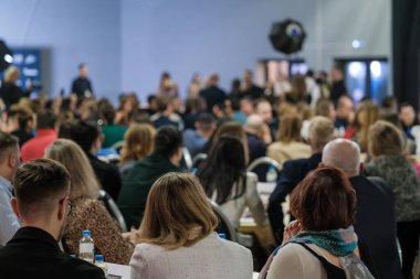 Resmi bir ortamda sunumların ve profesyonel etkileşimin yer aldığı bir konferansa katılan dinleyiciler.