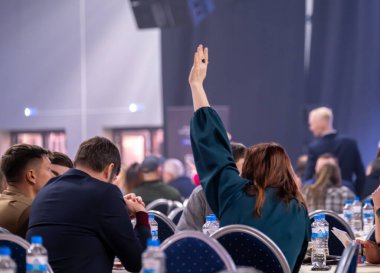 Konferansa katılanlar kalabalık salonda el kaldırarak eğitim, katılım ve nişanı resmediyorlar..