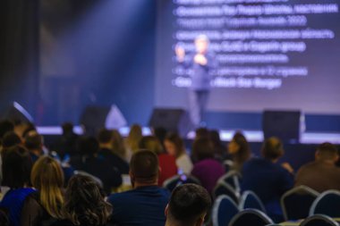 Odaklanmış seyirciler profesyonel bir konferans sırasında bir açılış konuşmasını dikkatle dinlerler..