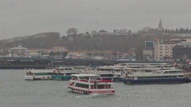 Tarihi İstanbul kıyısı yakınlarındaki bulutlu gökyüzü ve şehir manzaralı yolcu teknelerinin görüntüsü.