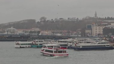 Tarihi İstanbul kıyısı yakınlarındaki bulutlu gökyüzü ve şehir manzaralı yolcu teknelerinin görüntüsü.