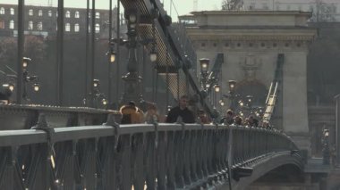 Budapeşte, Macaristan - 2 Nisan 2025: Turistler ve yerliler, güneş ışığı altında Budapeşte 'de tarihi bir köprü boyunca yürürken, mimari güzellikler gözler önüne seriliyor.
