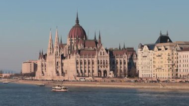 Macar Parlamento Binası açık gökyüzünün altında Tuna Nehri boyunca belirgin bir şekilde duruyor. İkonik mimari, şaşırtıcı tasarımı ve kültürel önemi nedeniyle turistleri Budapeşte 'ye çekiyor..