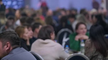 Bir grup birey, geniş bir alanda resmi bir iş konferansında toplandı. Resim, bir sunum veya olay sırasında izleyicinin dikkatini yakalar.