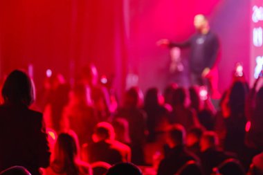 Şiddetli kırmızı ışık altında canlı yayında bulanık seyirci silueti enerjik bir atmosfer yaratıyor