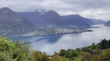 Dağlarla dolu Iago di Como 'nun huzurlu manzarası, yansıtıcı su ve yemyeşil..