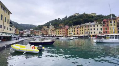 Portofino, İtalya - 10 Kasım 2024: Portofino manzarası, canlı binalar, yeşil tepeler ve sakin sularda tekneleri olan liman.