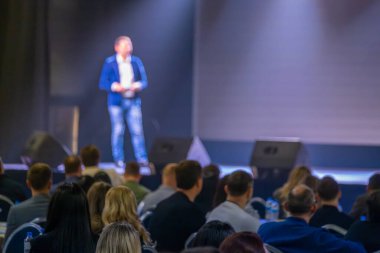 Seminerde seyircilere seslenen konuşmacı, kalabalığı dinleme ve sahne kurulumuna odaklandı