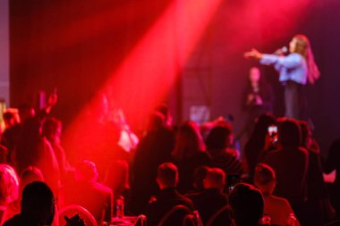 Gece kulübünde kırmızı ışıkların altında eğlenen kalabalığın olduğu enerjik canlı müzik performansı