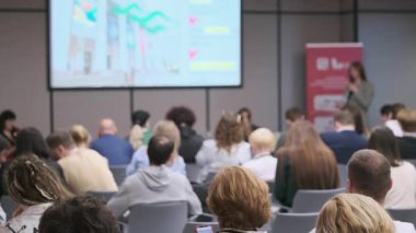 Konferans odasında seminere katılan insanlar sahnede aktif olarak bir konuşmacıyı dinliyorlar..