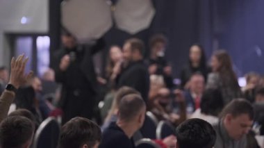 Seyirciler, konuşmacılar ve kamera ekibiyle birlikte iş konferansına dikkatle katılıyor.