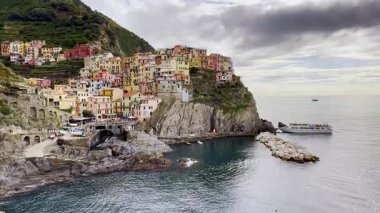 Uçuruma tünemiş renkli evler. Sakin deniz manzaralı. Yakınındaki teknesi Cinque Terre..
