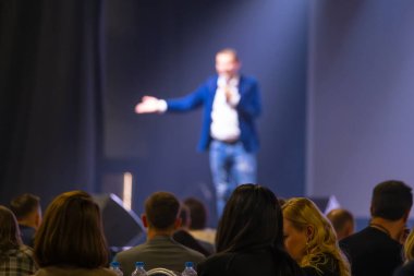 Hoparlörle konferans ayarları loş ışıklandırmayla izleyicilere sunum yapıyor.