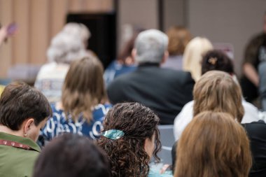 Bir eğitim seminerinde veya kapalı bir ortamda dikkatle dinleyen izleyiciler