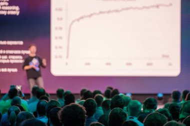 İzleyiciler dikkatle dinlerken sunucuyu ekranda verileri açıklarken gösteren konferans oturumu