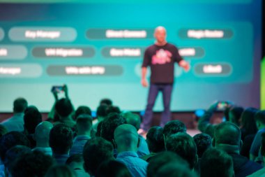 Konferans konuşmacısı, katılımcı dinleyicilerle şirket ortamında teknolojiyle ilgili kavramları tartışıyor.