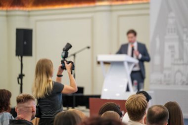 Profesyonel bir fotoğrafçıyla resmi bir iş etkinliğine katılıp konuşmacıların sunumunu belgelemek.